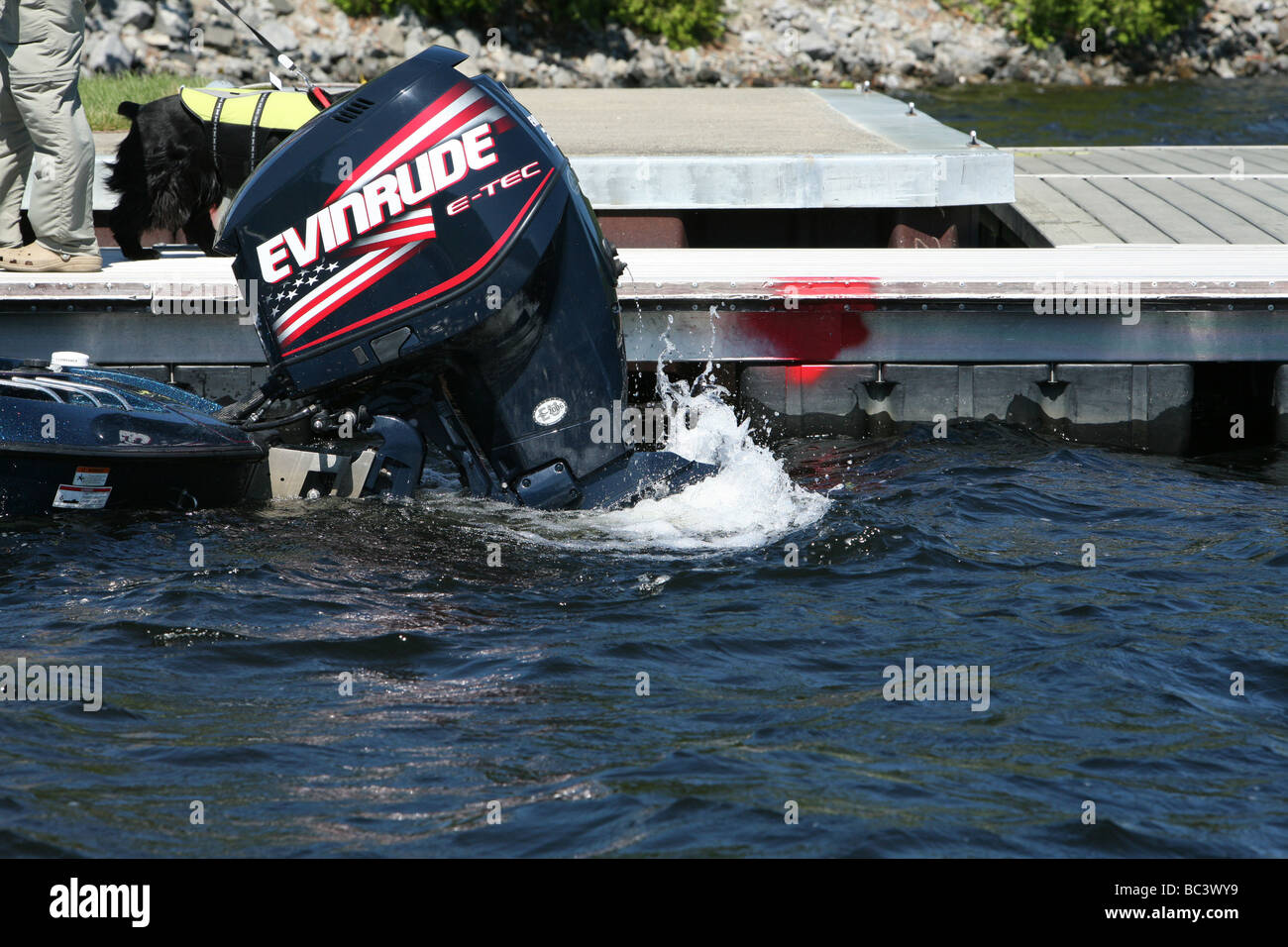 A 225 e-tec Evinrude outboard motor shot in close up with its prop churning and splashing up the water at a dock. Stock Photo
