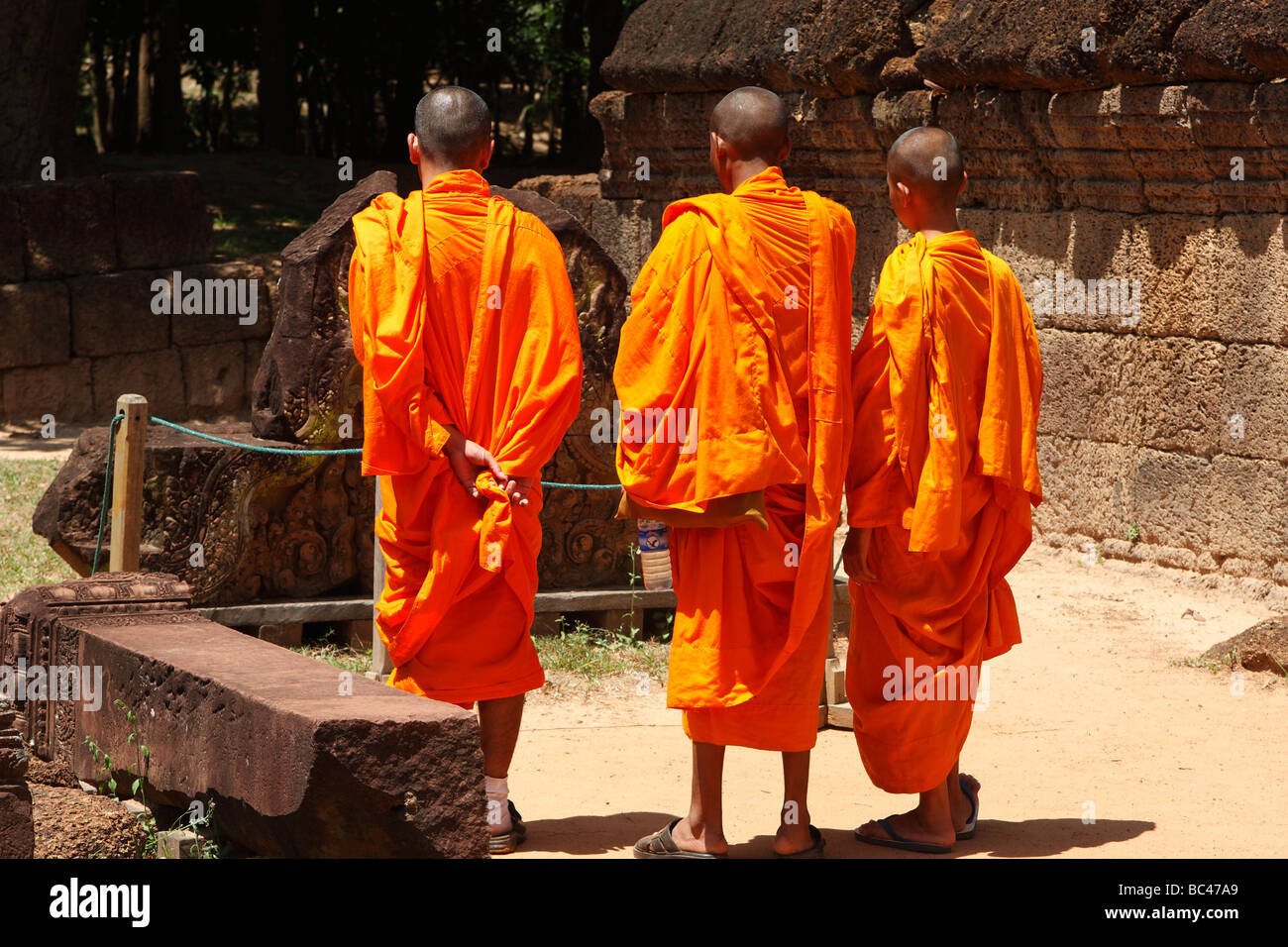 Buddhist monks wearing orange robes standing in the temple ruins of 'Banteay Srei', Angkor, Cambodia Stock Photo
