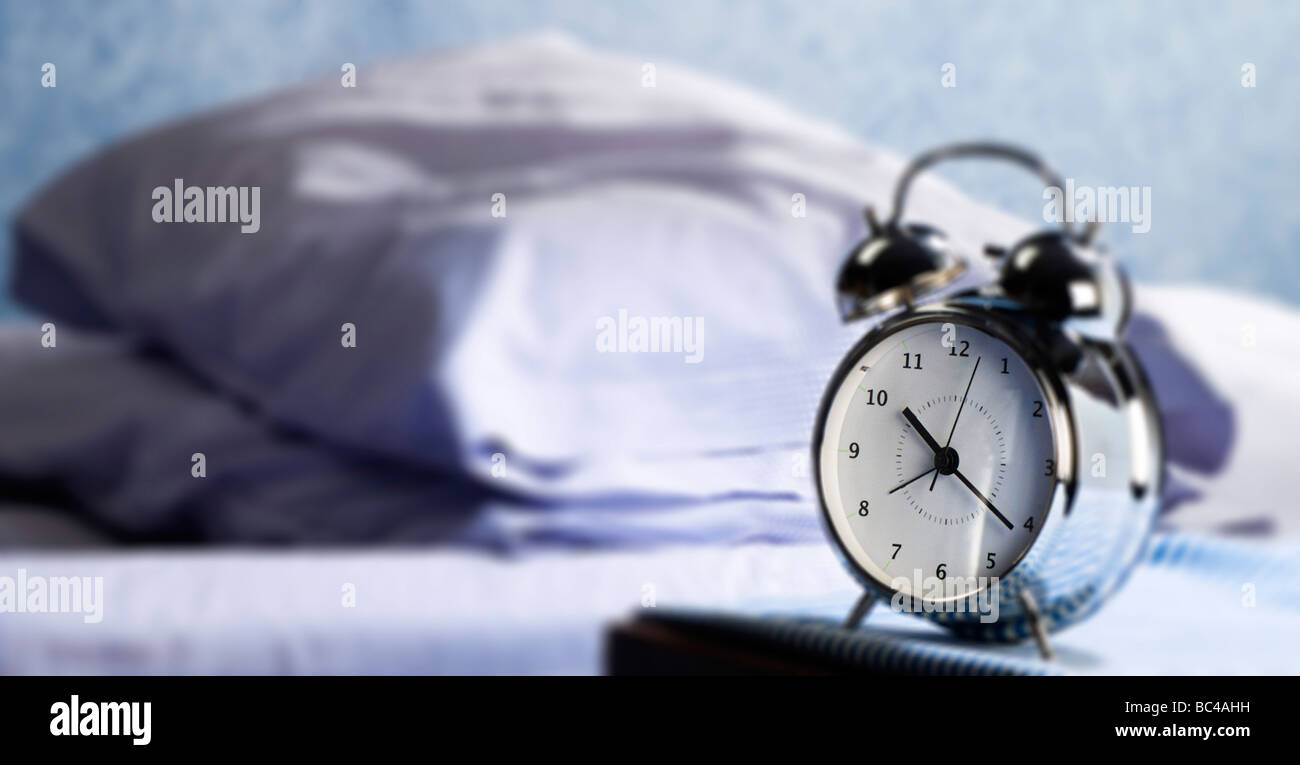Alarm clock beside a bed Stock Photo Alamy