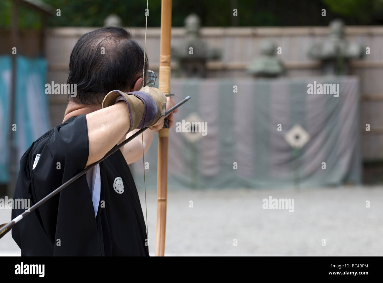 A man performing the art of archery or kyudo concentrates before releasing the arrow at a