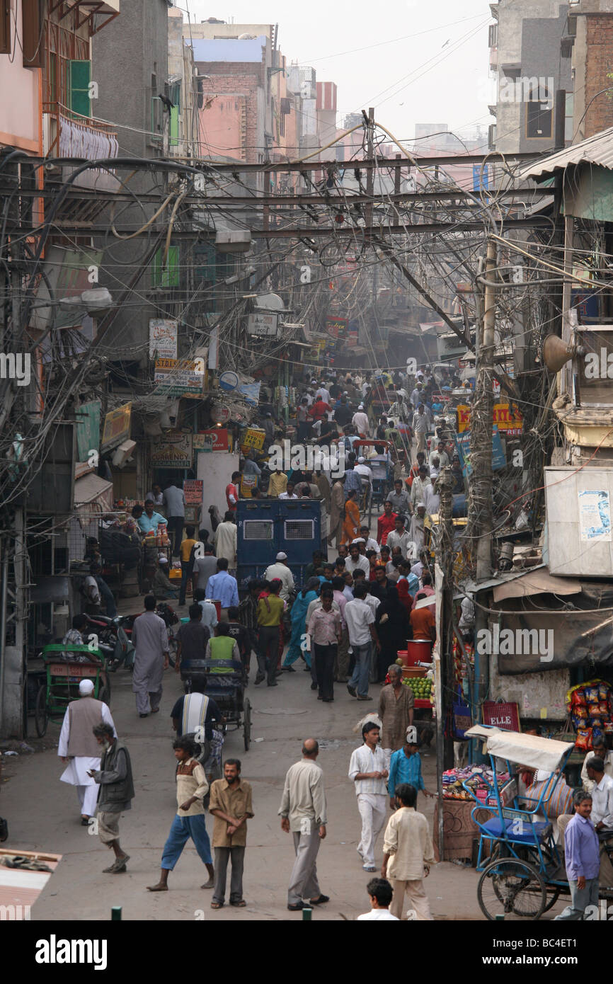 Chaotic street scene in New Delhi with hustle and bustle under the typical makeshift cables and wiring. Stock Photo