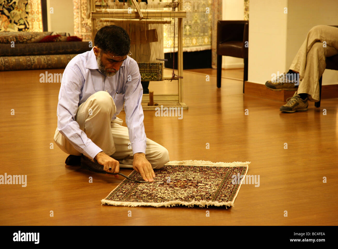 Tradesmen showing and demonstrating locally produced rugs to tourists in a shop in New Delhi