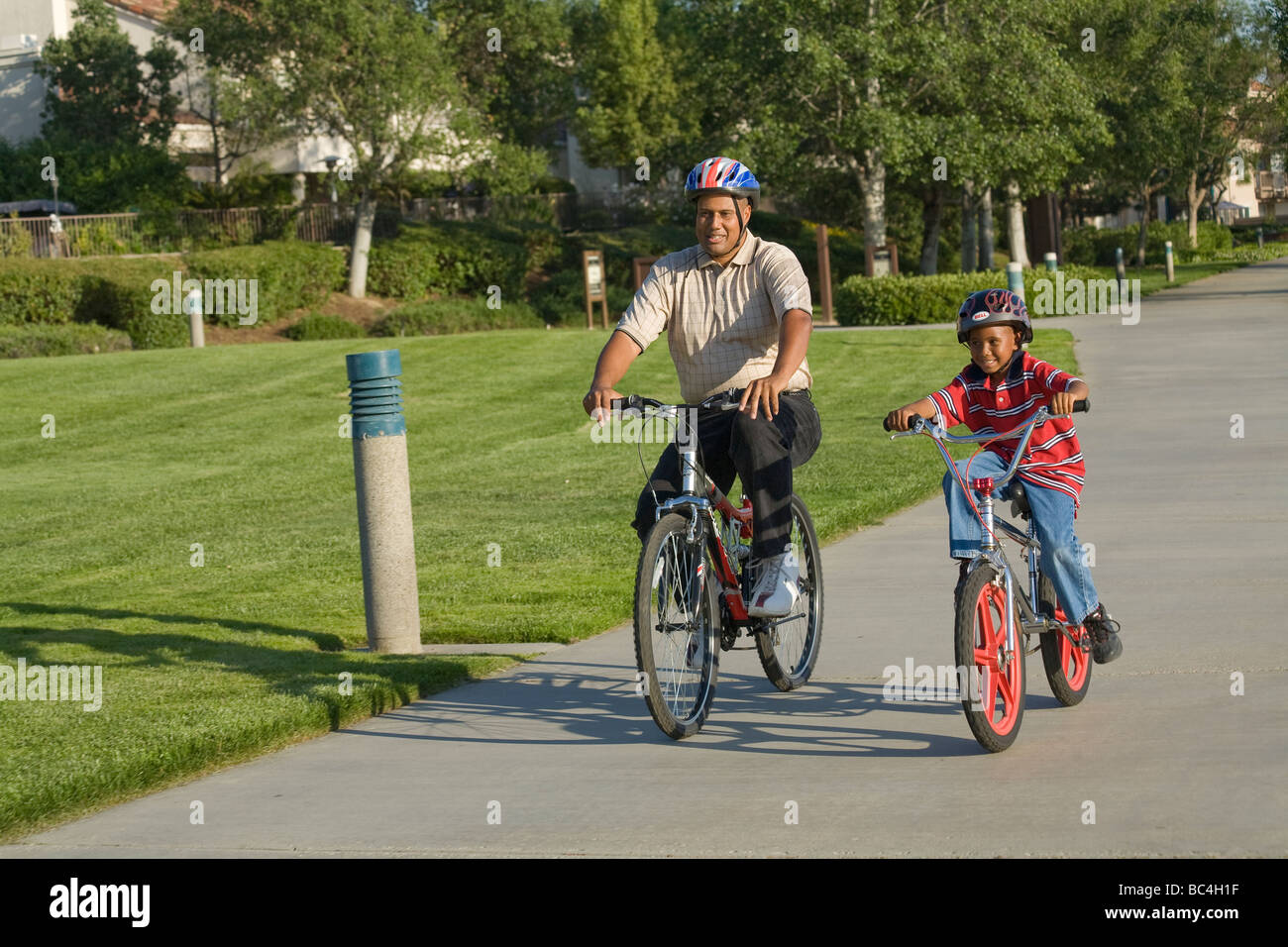 Father child children riding bikes bike bicycle bicycling bicycles helmet together outside.California ethnic Parent 5-6-7-8 years year old  MR  © Myrleen Pearson Stock Photo