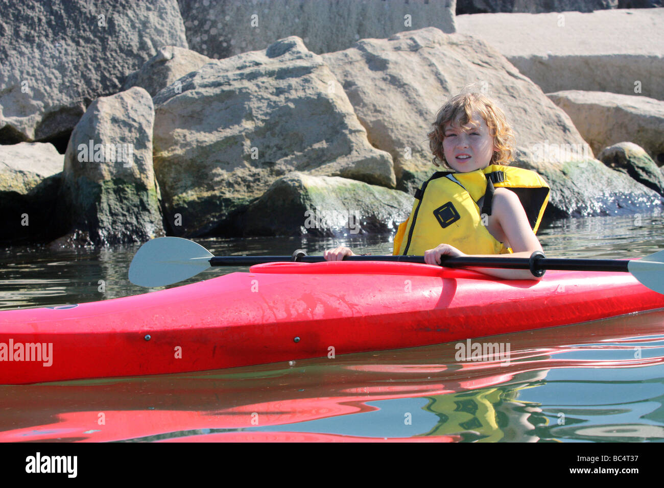 Boy paddling kayak near rocks Stock Photo Alamy