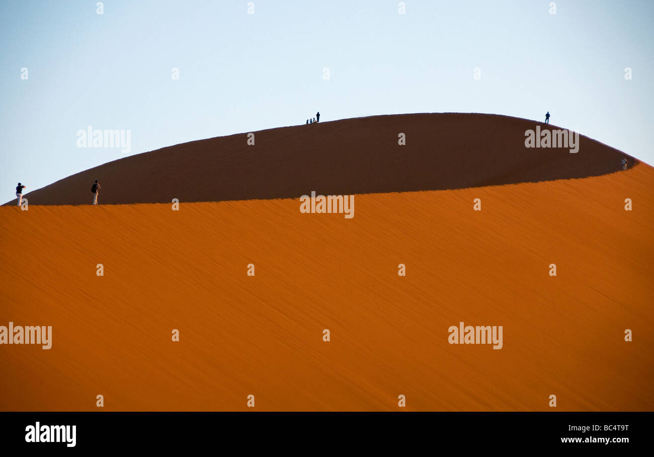 tourists on a giant sand dune at dawn in Sossusvlei National Park in ...