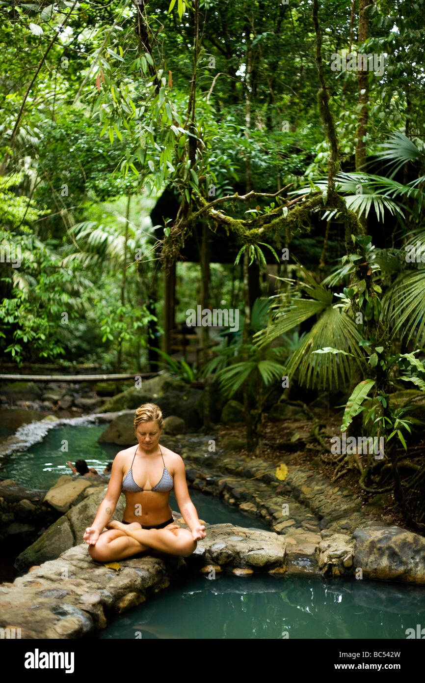 A young woman assumes the Lotus position in the thermal pools of Bosque Termales located close to La Fortuna. Stock Photo