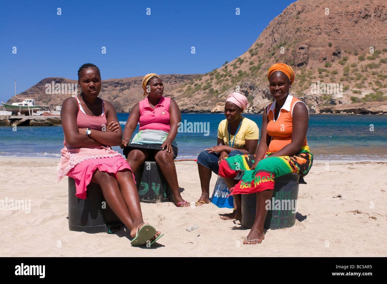 Dark skinned women sitting at sandbeach and talking to each other Tarrafal Santiago Cabo Verde Africa Stock Photo