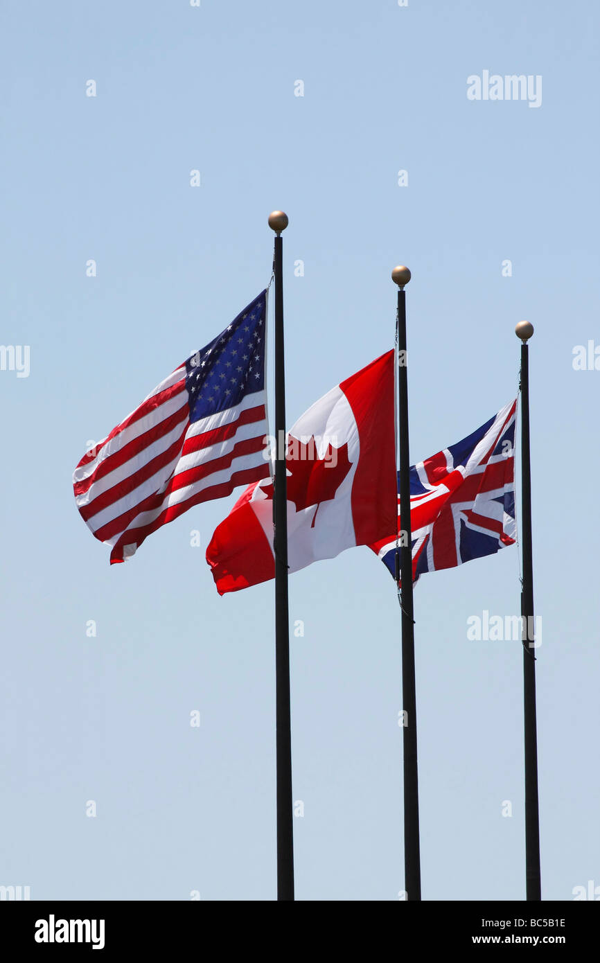 Flags USA British Canadian on a pole waving and wind cut out cutout isolated on blue sky background in Ohio USA hi-res Stock Photo