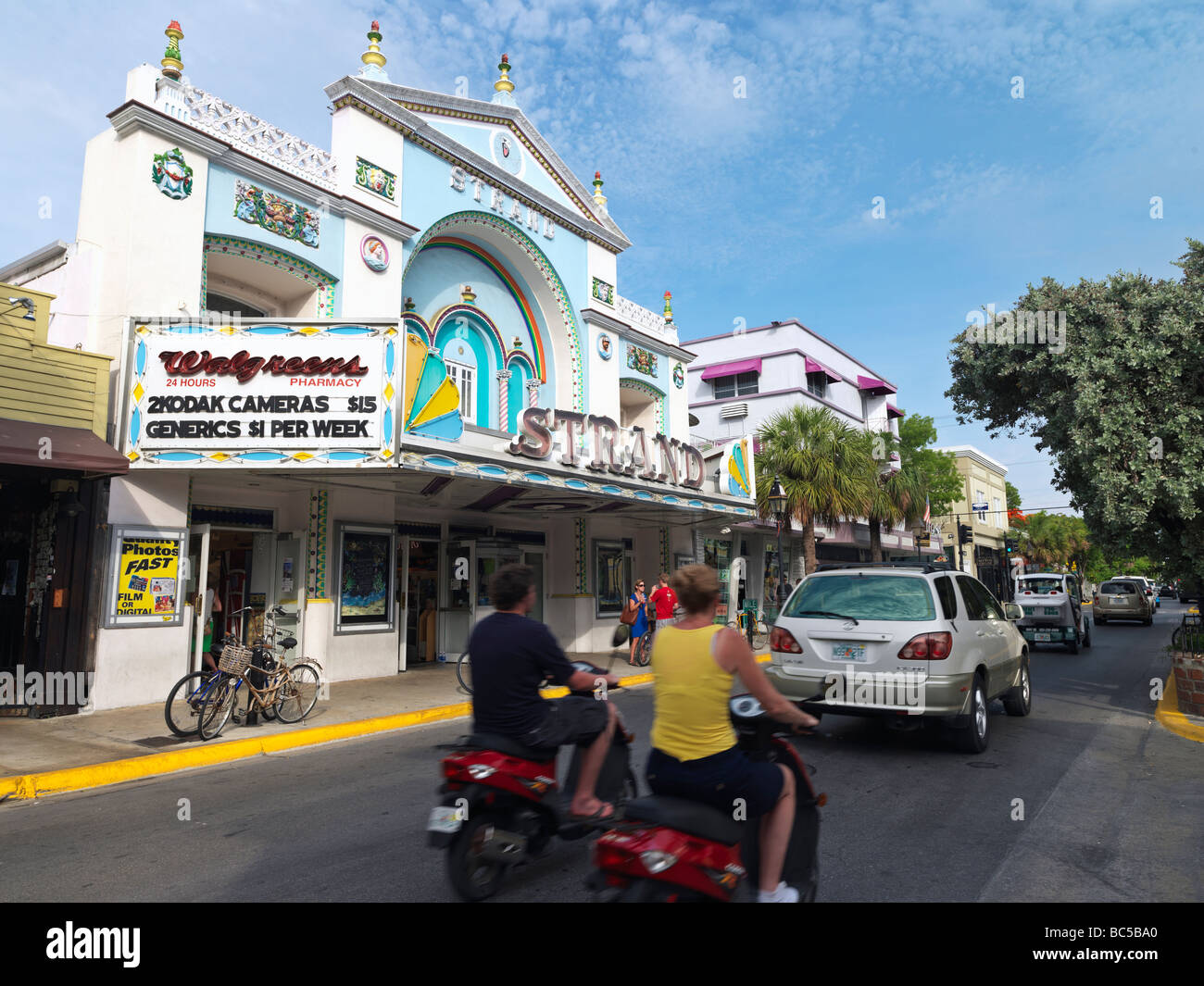 couple on moped on Duval Street passing by the Strand Theater Stock Photo