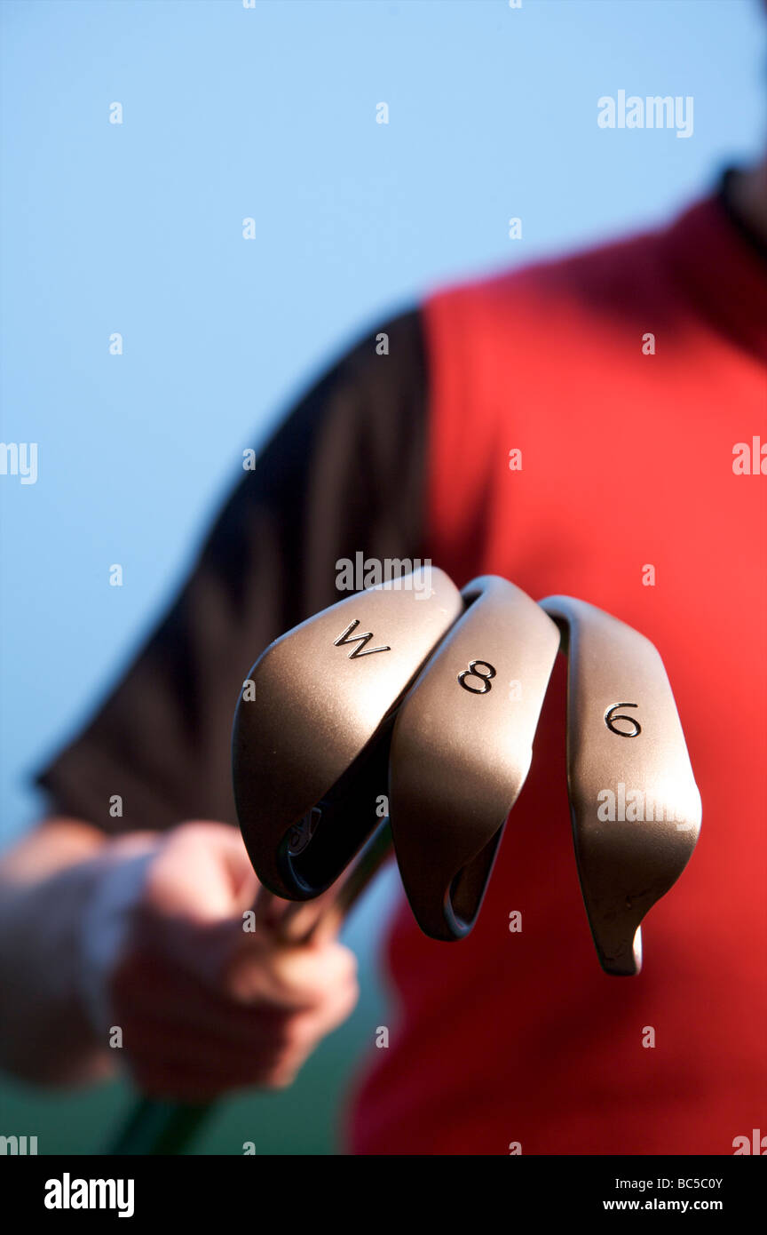Golfer holding three golf clubs Stock Photo