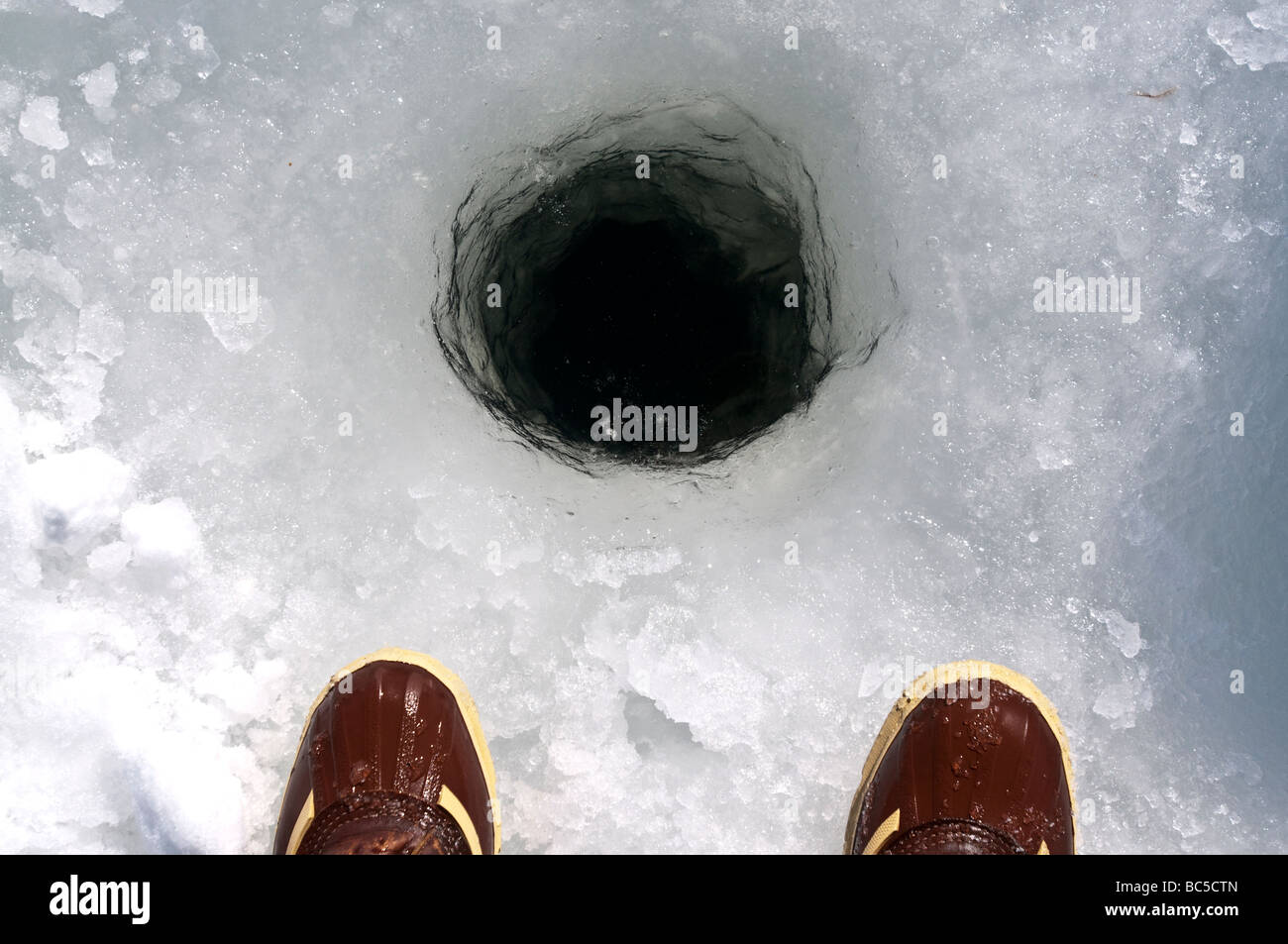 two boots and an ice fishing hole. Stock Photo