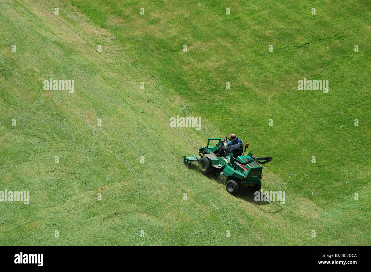 aerial view of man cutting grass with sit-on lawn mower, England, UK Stock Photo