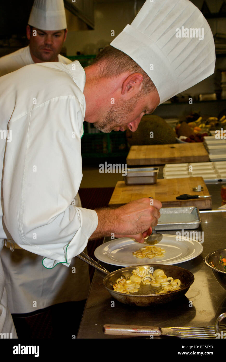 Chef Daniel Buss starting to carefully plate his entree with a bed of sauteed hearts of palm Stock Photo