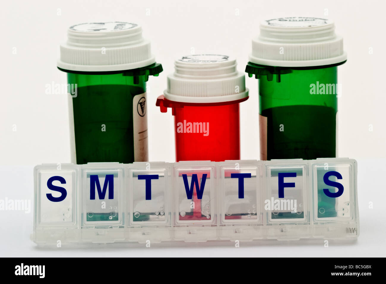 Three empty prescription bottles with caps behind an empty daily plastic vitamin pill holder Stock Photo