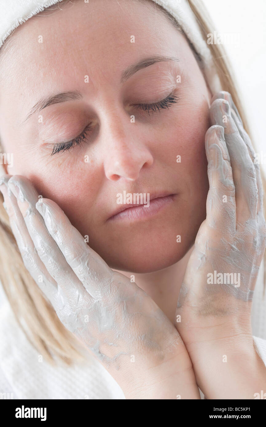 Young woman putting cream on her face - Stock Photo