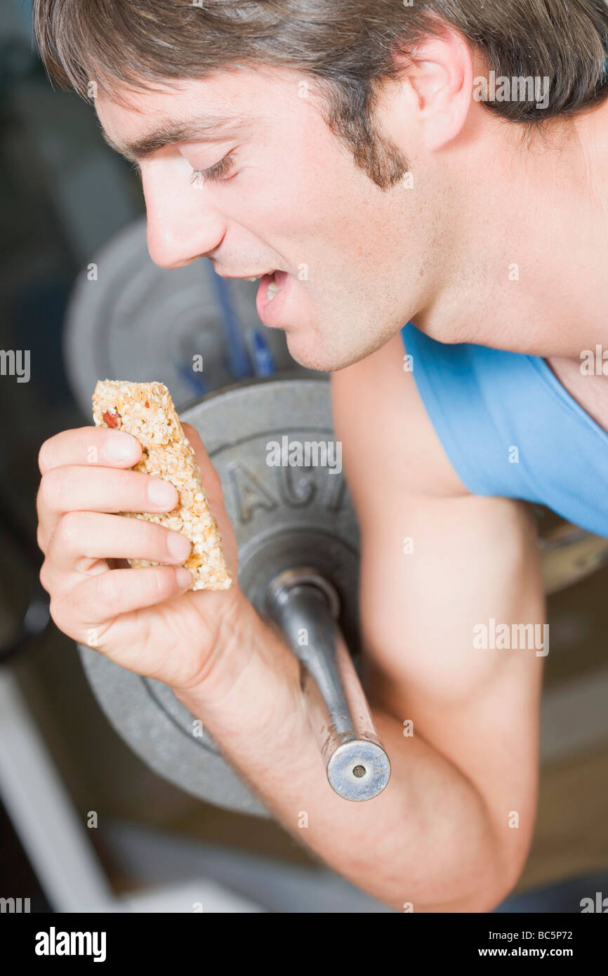 Man eating muesli bar on weight bench Stock Photo Alamy