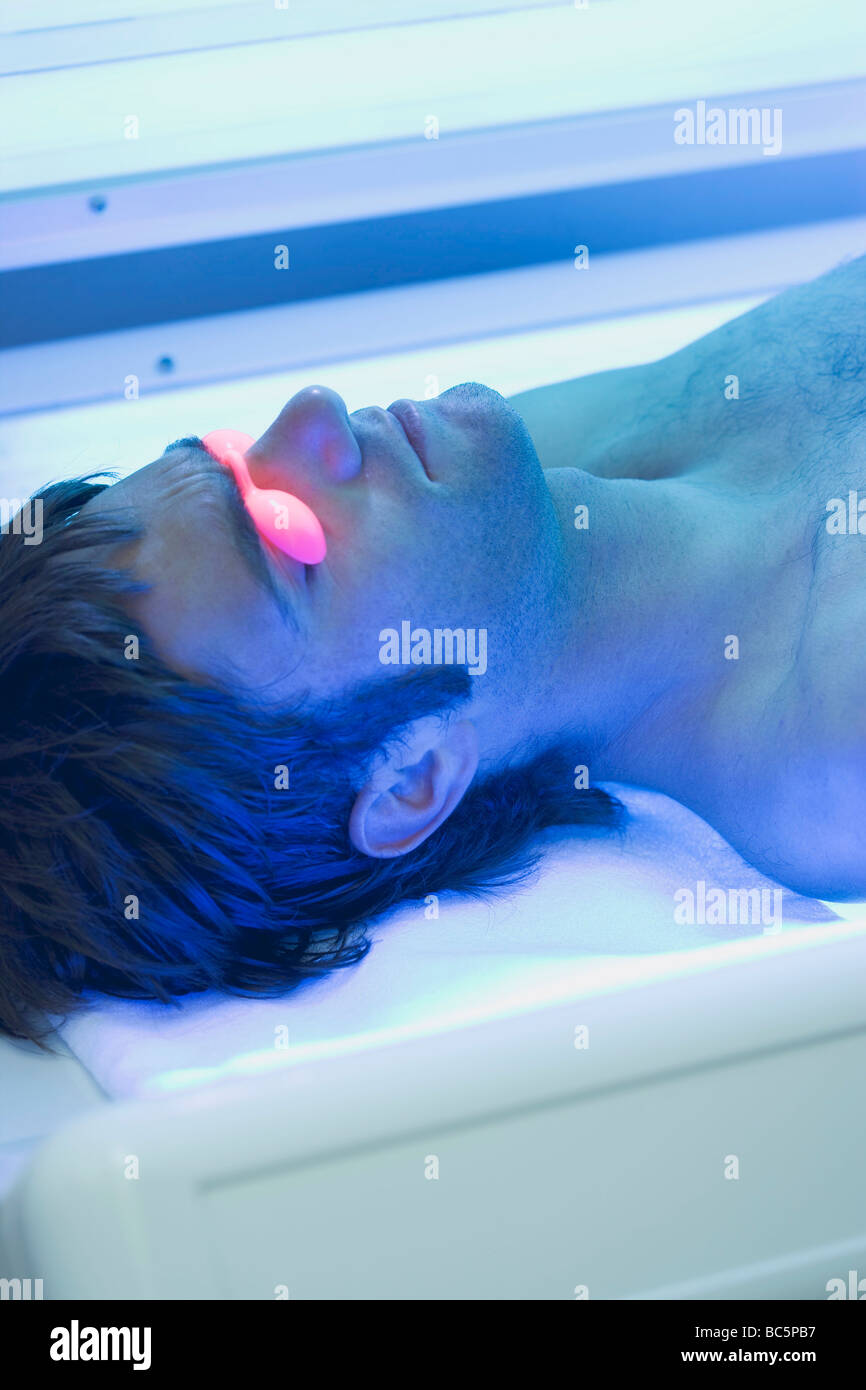 Young man in tanning goggles lying on tanning bed Stock Photo Alamy