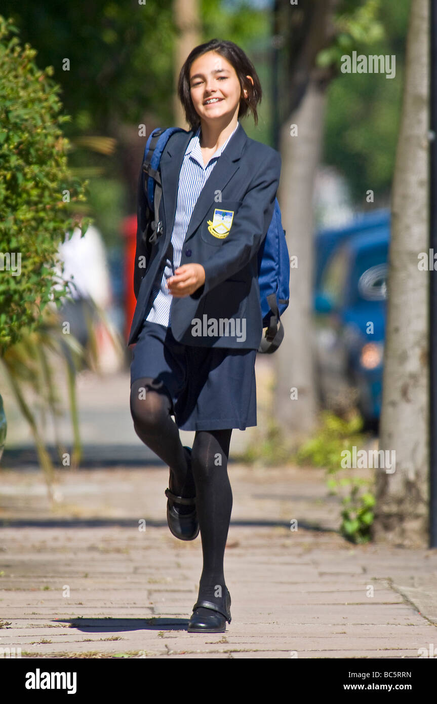 A young caucasian girl (12) smiling while running home/to school wearing her uniform. Stock Photo