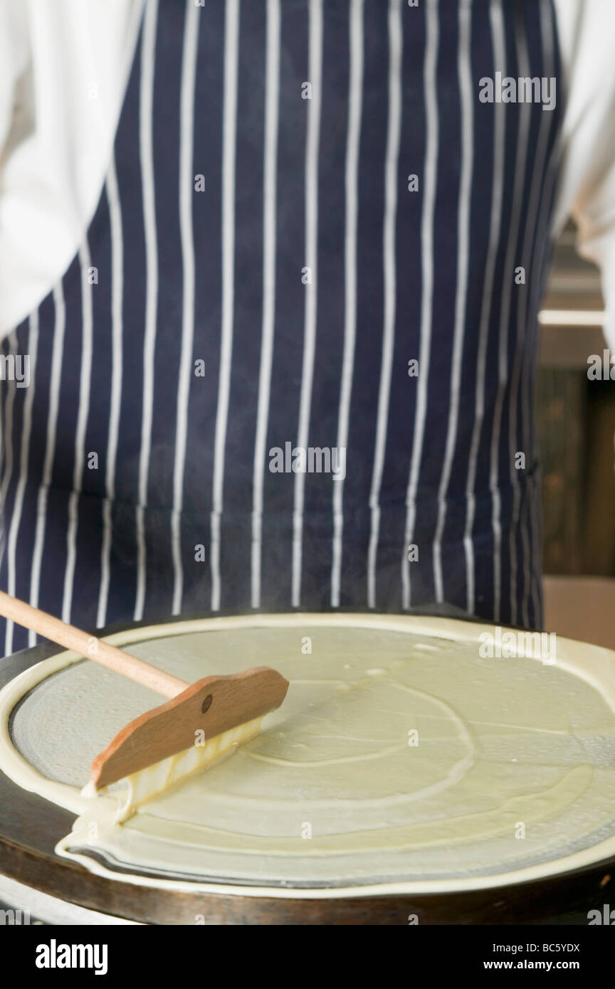 Spreading pancake mixture on hotplate - Stock Photo