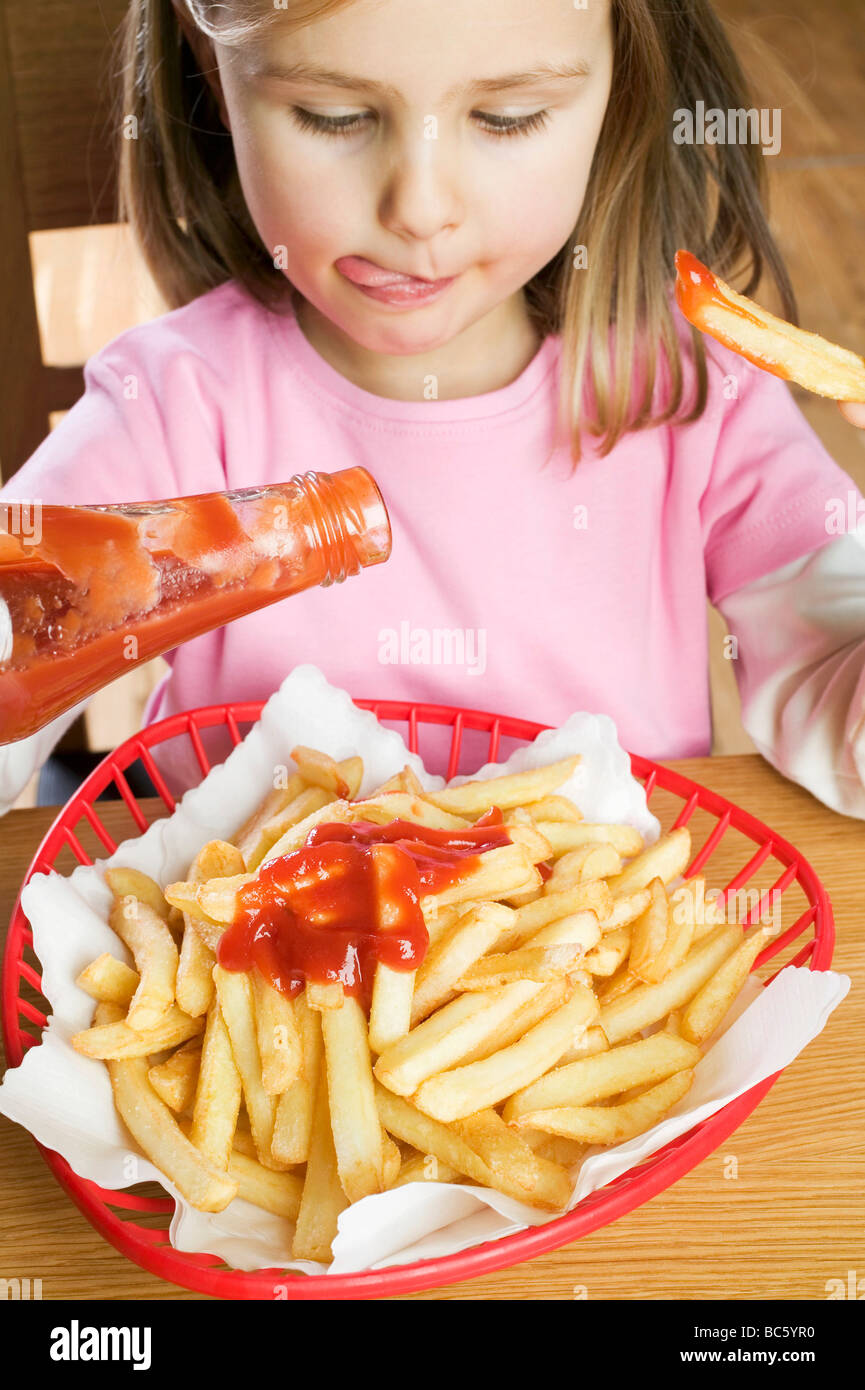 Girl eating chips with ketchup Stock Photo Alamy