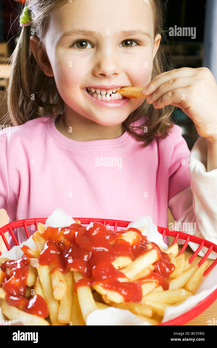 Girl eating chips with ketchup Stock Photo Alamy