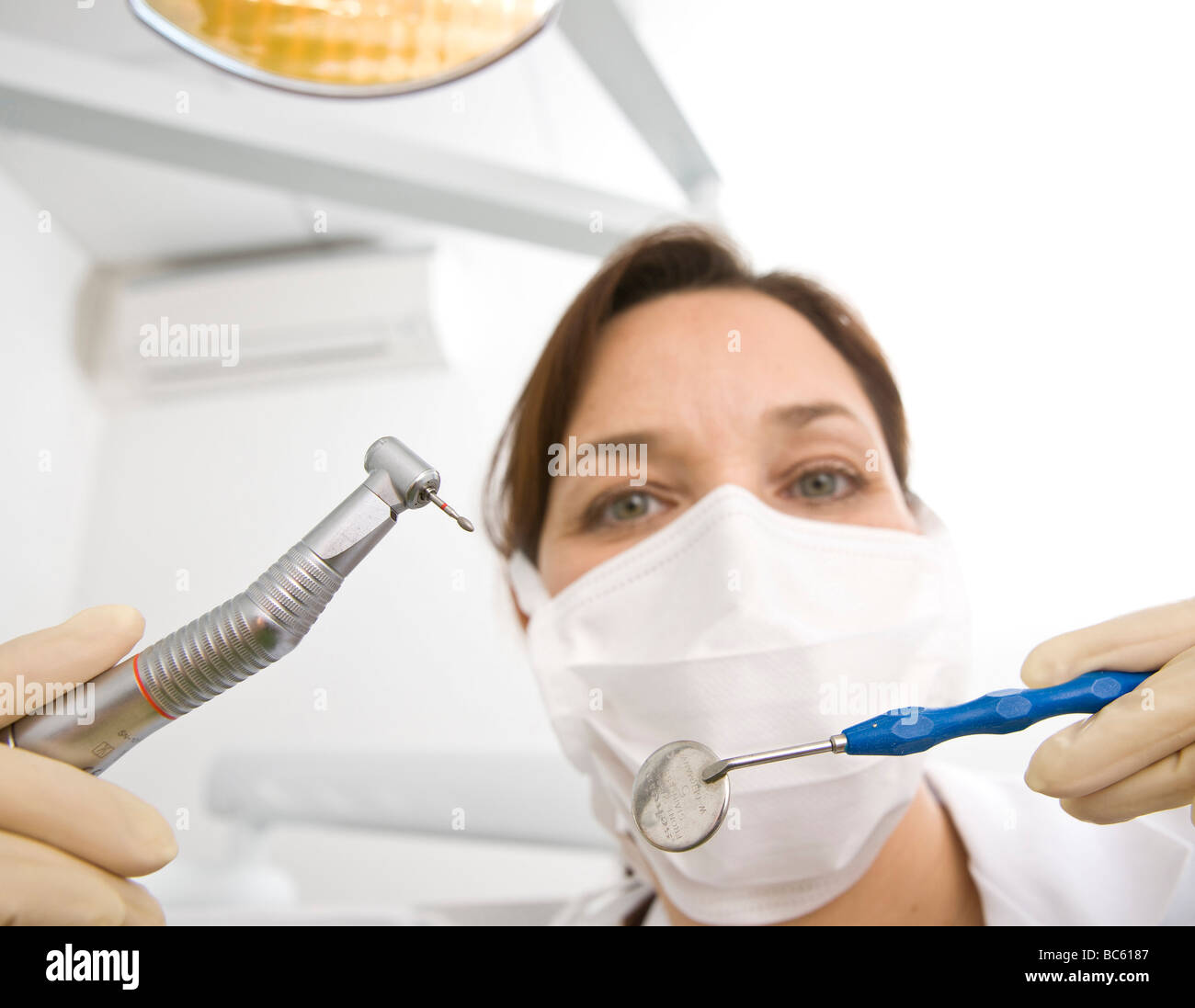 Portrait of female dentist holding dental drill and angled mirror Stock Photo