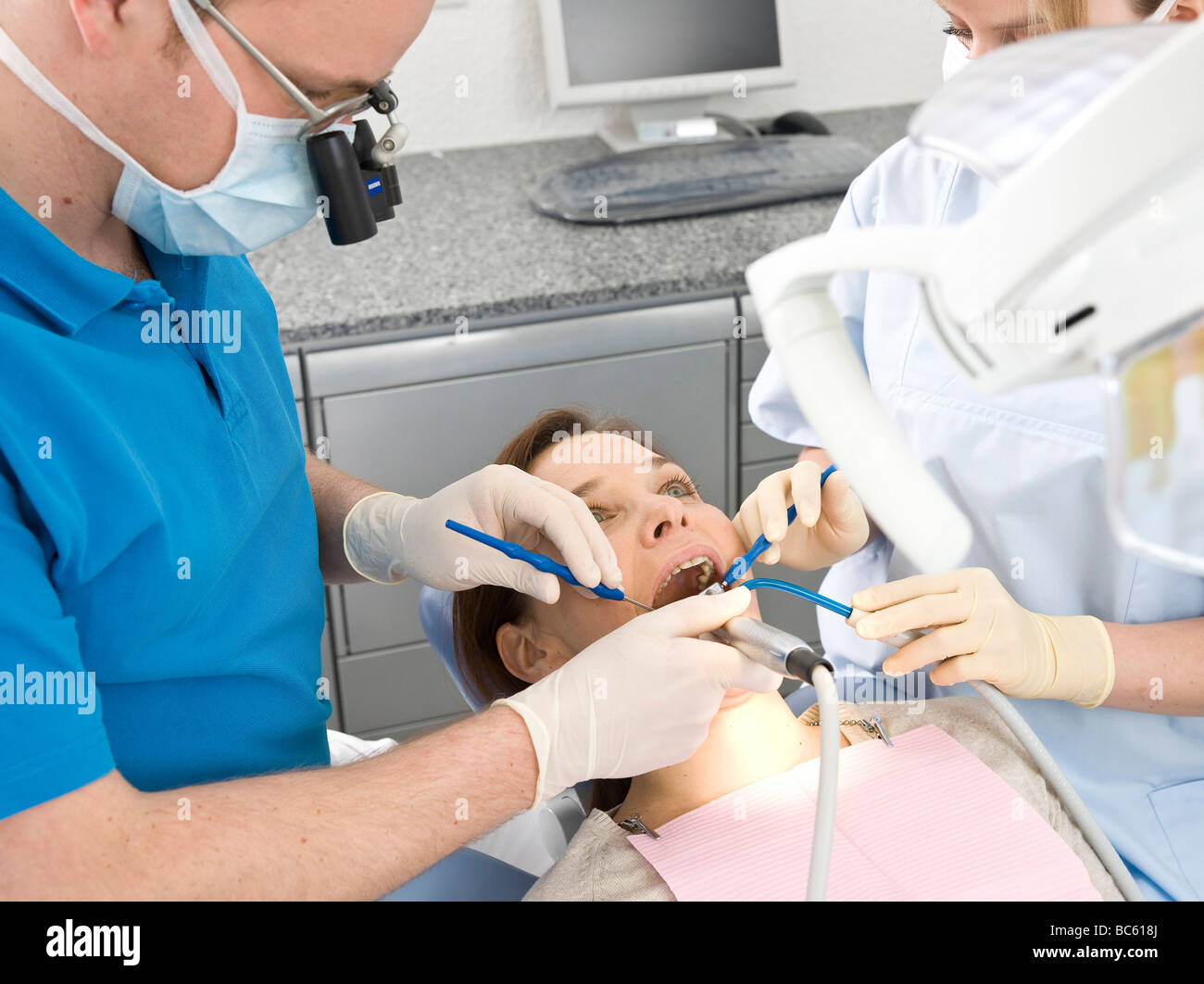 Male dentist and assistant examining patient's teeth Stock Photo