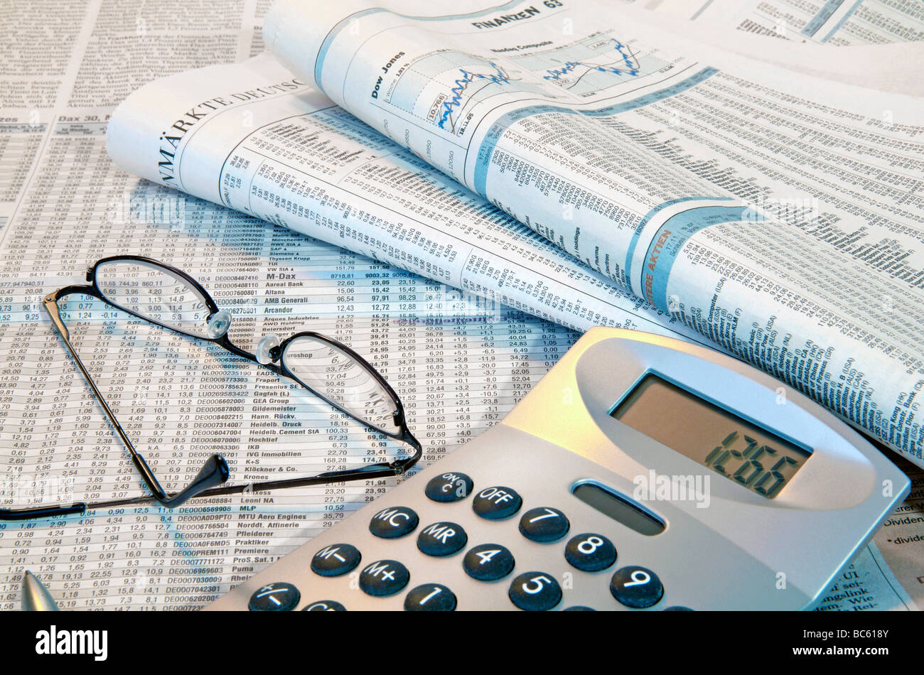 Close-up of financial newspapers with eyeglass and calculator Stock Photo