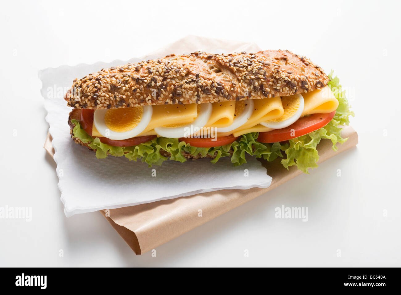 Granary roll filled with egg, cheese, tomato and lettuce - Stock Photo