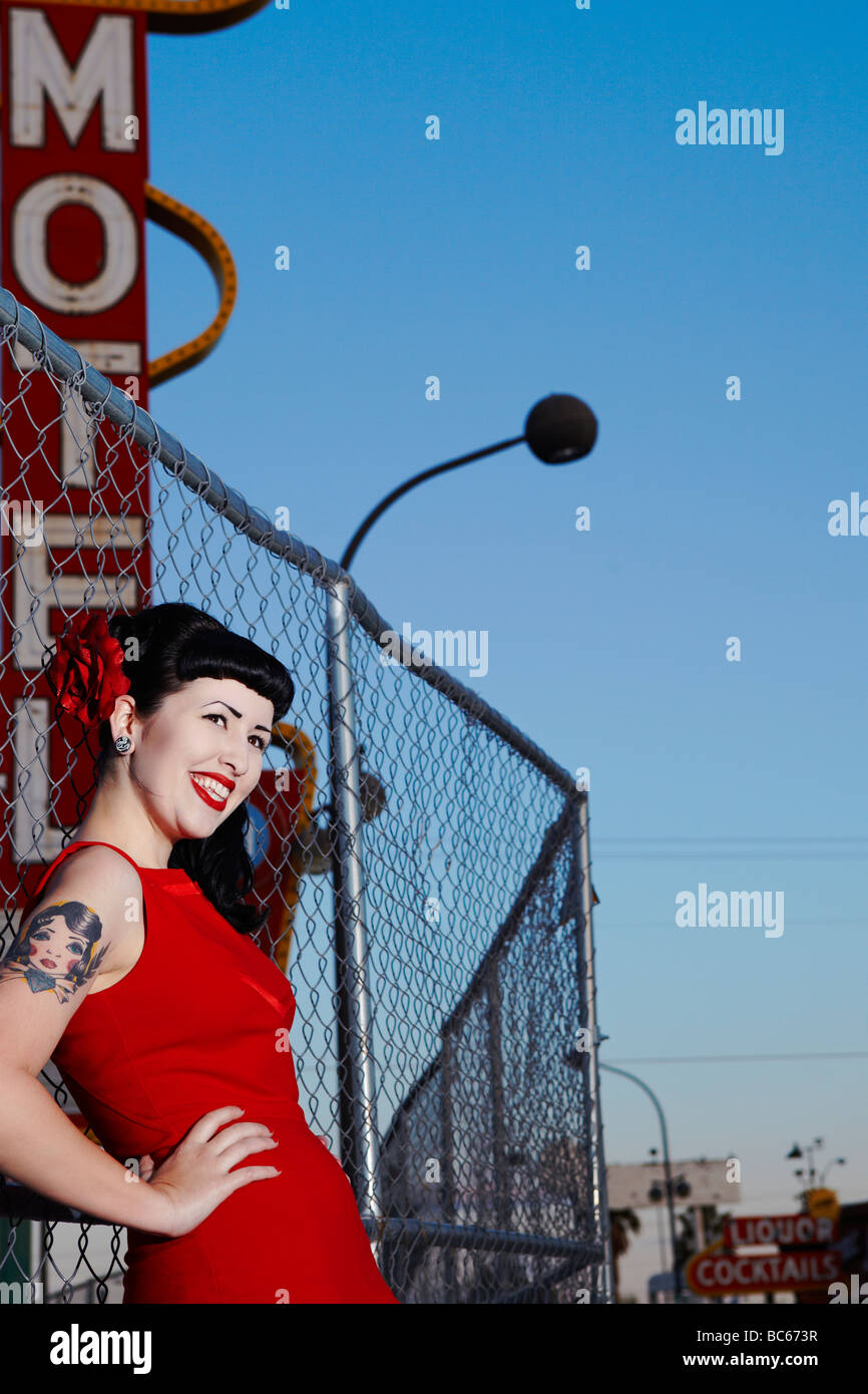 retro young woman with a tatoo in front of an old motel sign smiling Stock Photo