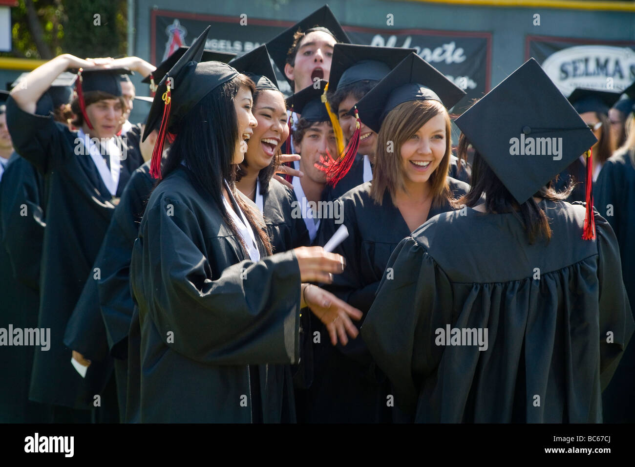 Happy senior high school seniors in cap and gown enjoy each others company as they prepare to graduate in San Clemente CA Stock Photo