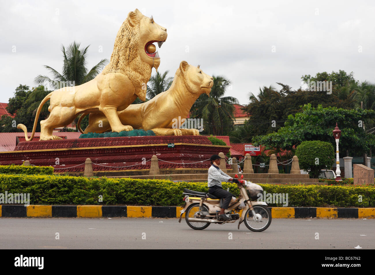 Cambodian man riding moped around 'Golden Lion' Roundabout, Sihanoukville, Cambodia Stock Photo