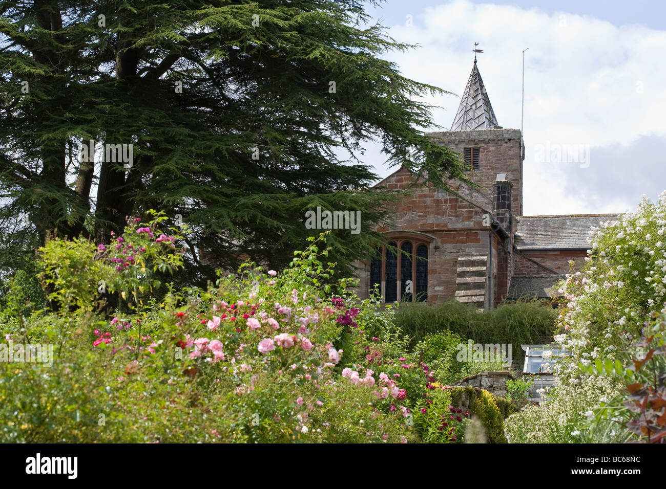 St Laurence Saxon Church beyond traditional English country garden Morland Cumbria UK Stock Photo