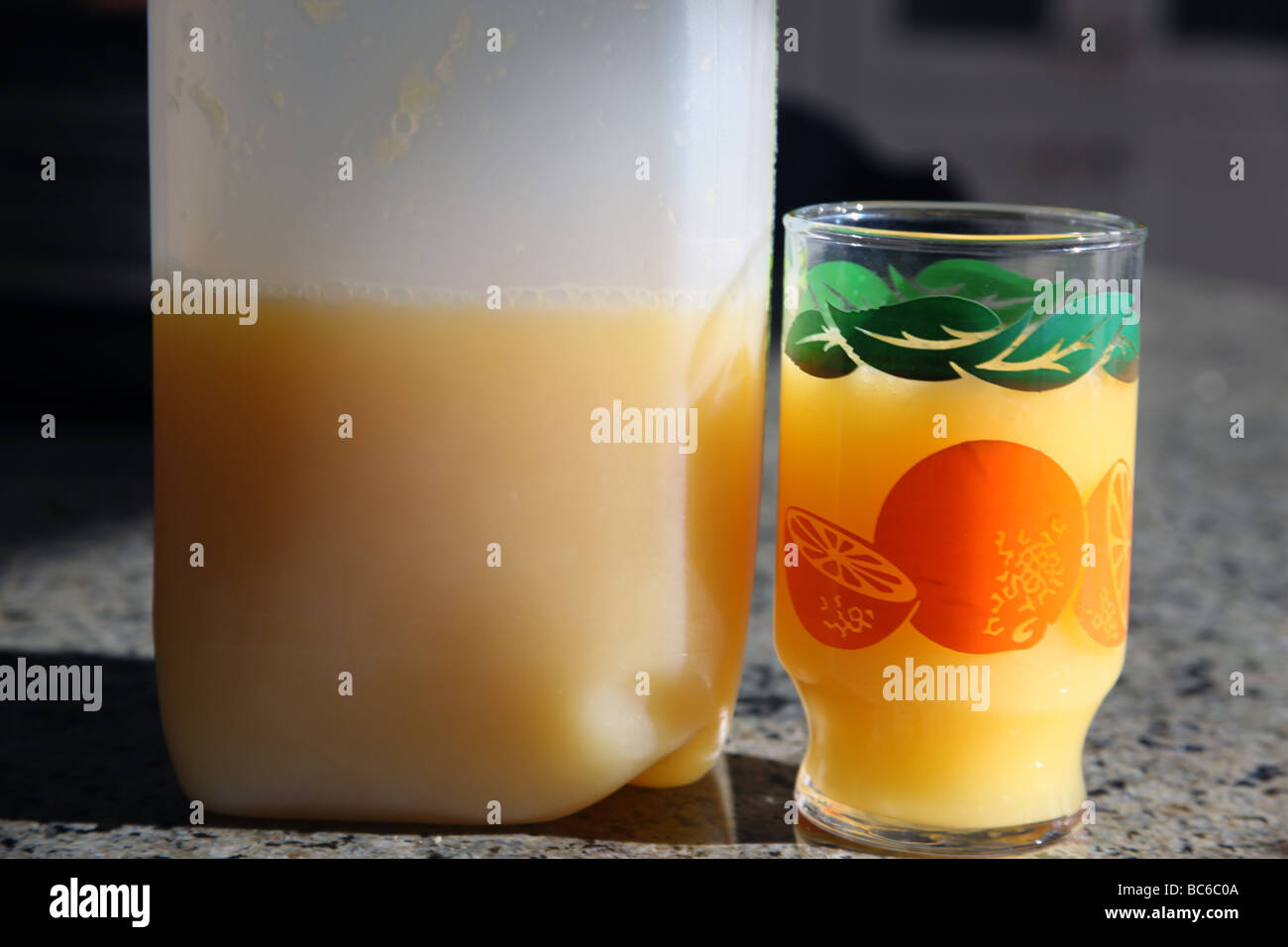 Bottle of freshly squeezed orange juice next to vintage orange juice glass Stock Photo