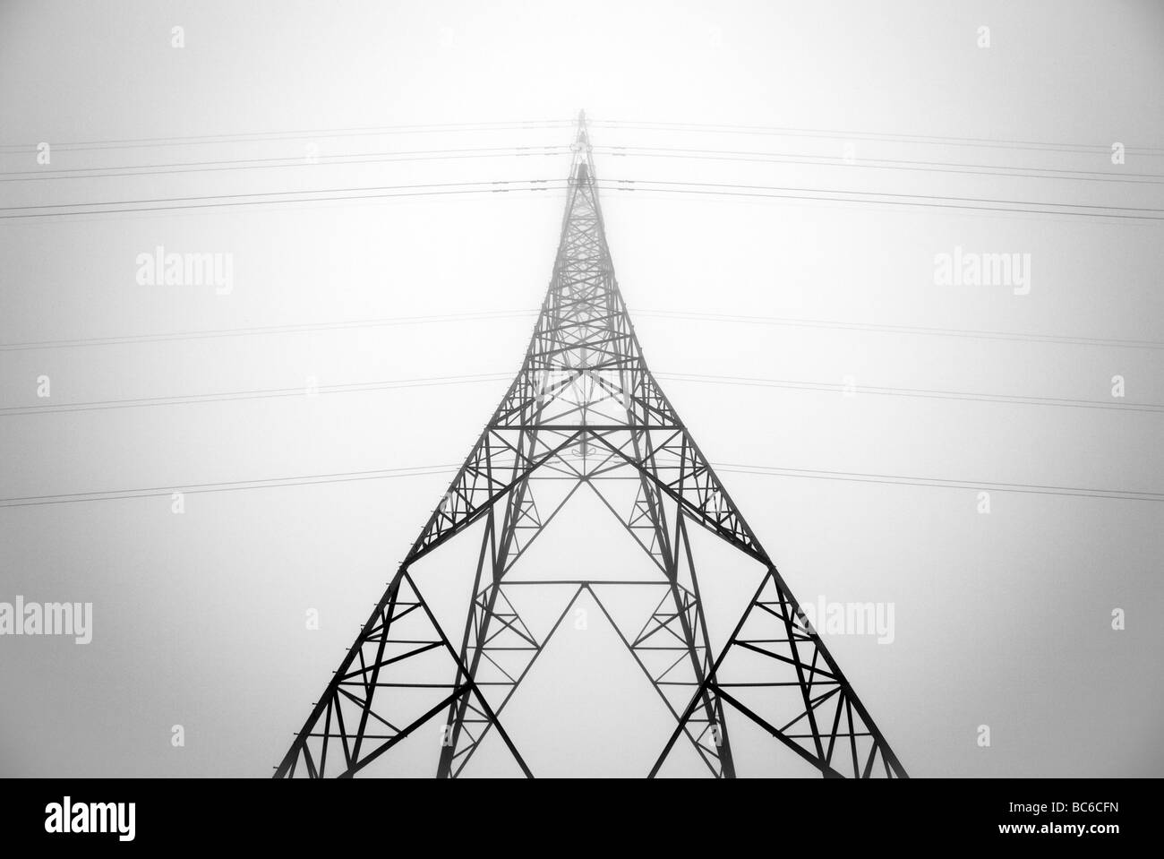 Looking up at an electricity pylon through the mist Stock Photo
