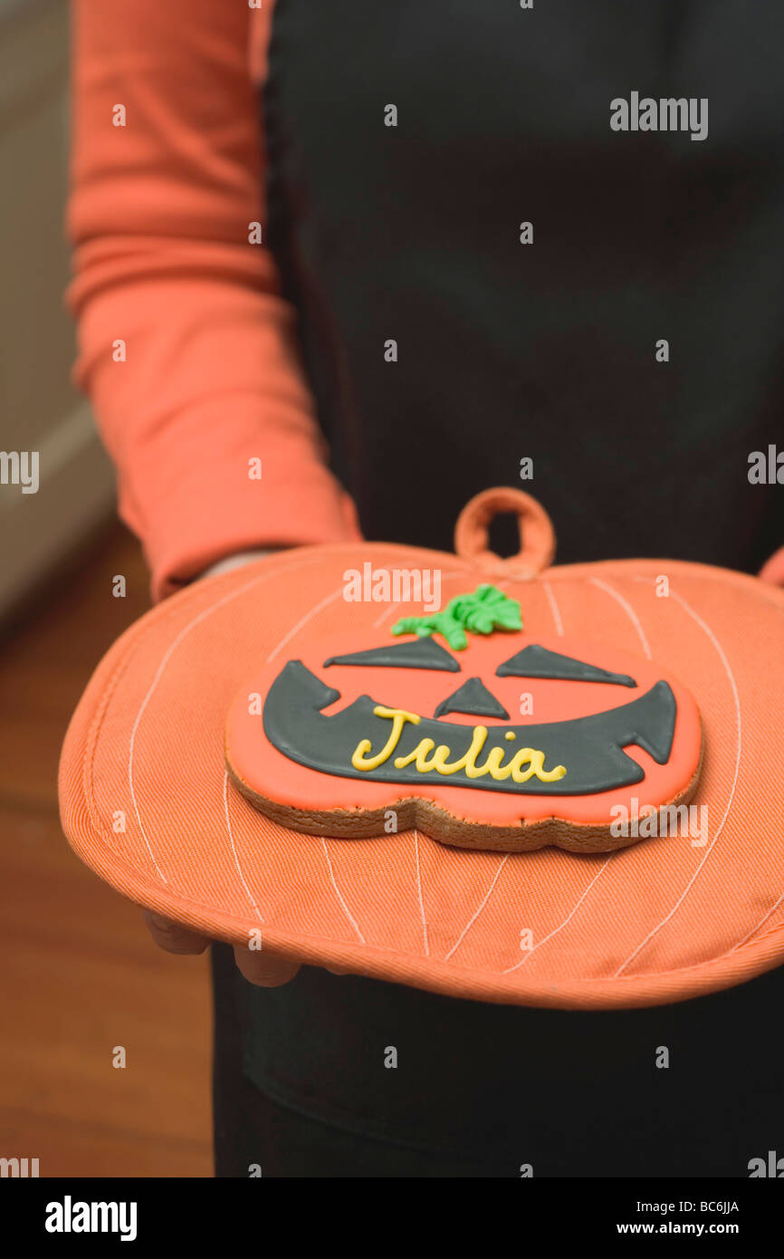 Hands holding Halloween biscuit with name on pot holder - Stock Photo