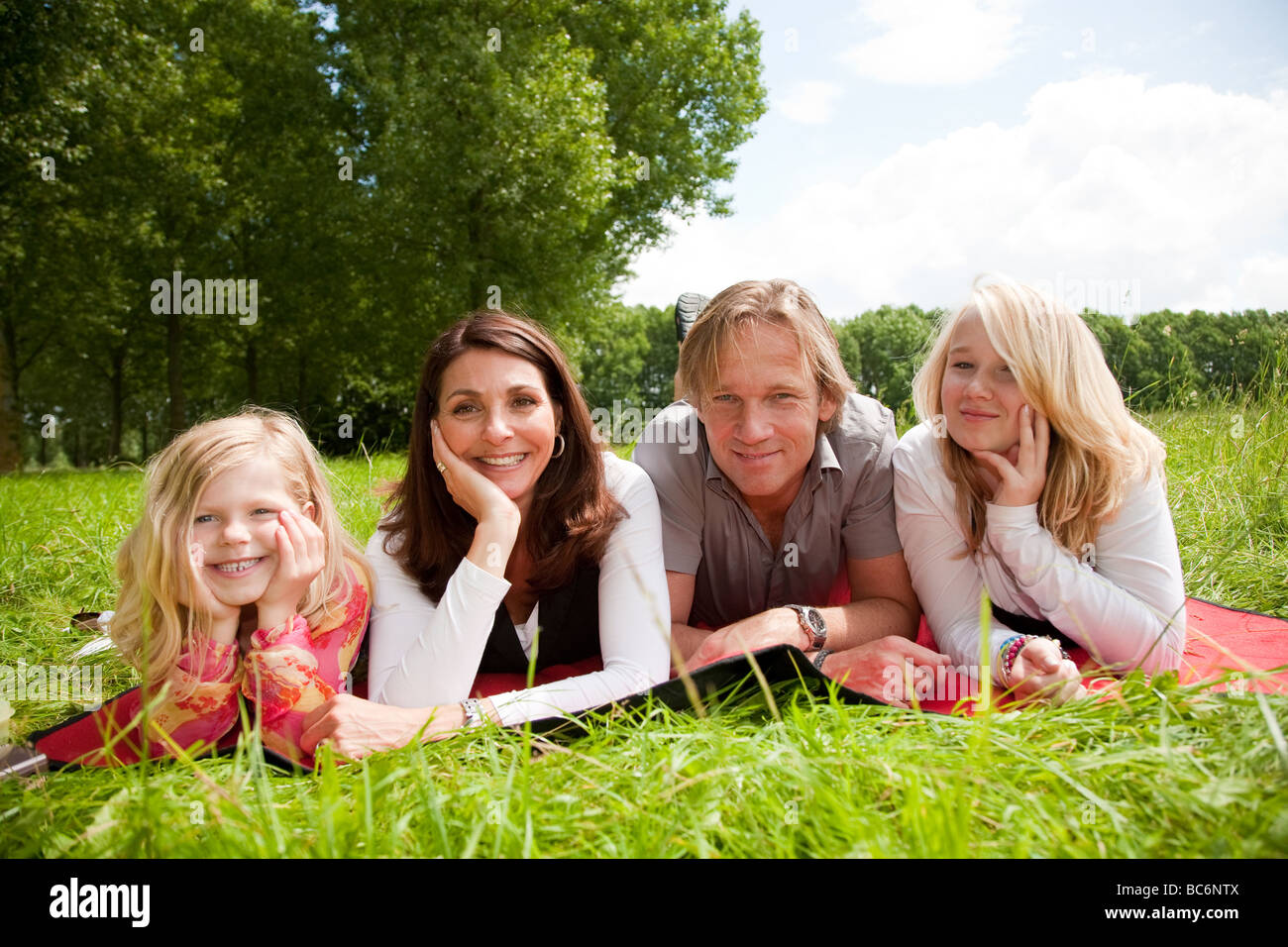 Adorable and beautiful young family lying in the field Stock Photo