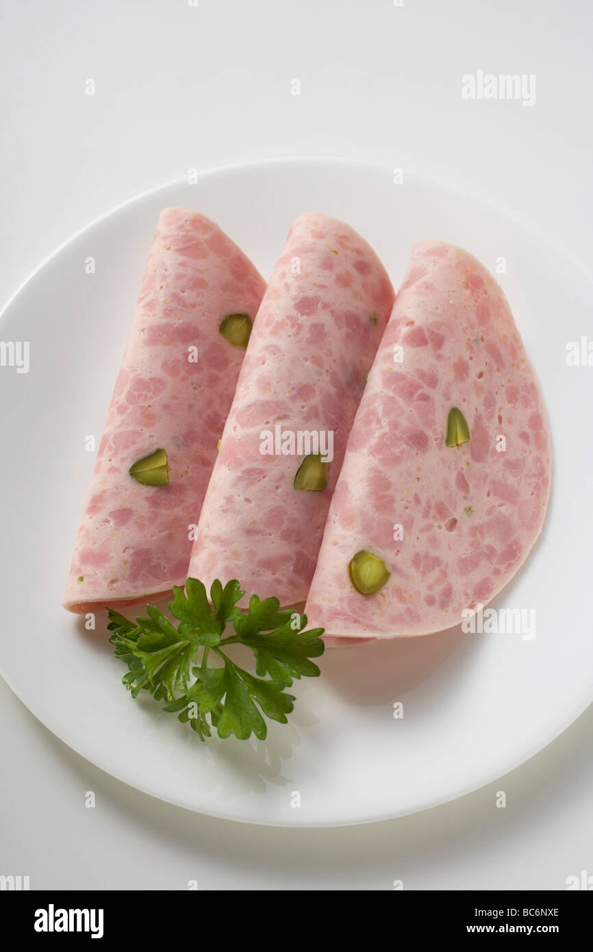 Three slices of Bierschinken (ham sausage) with parsley on plate - Stock Photo