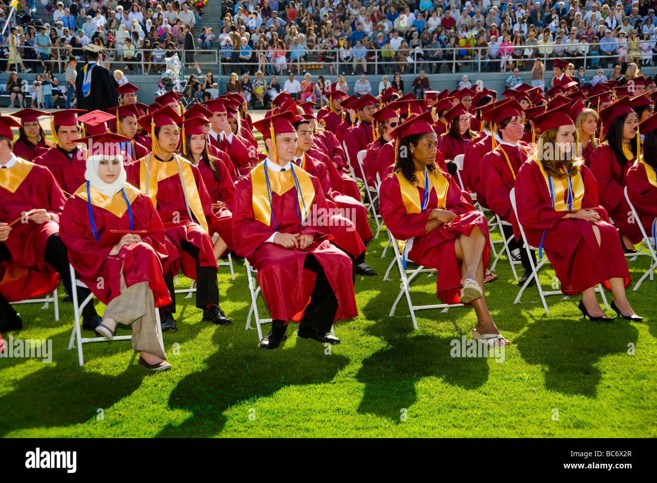 Wearing caps and gowns high school seniors participate in graduation exercises in Huntington Beach CA Stock Photo