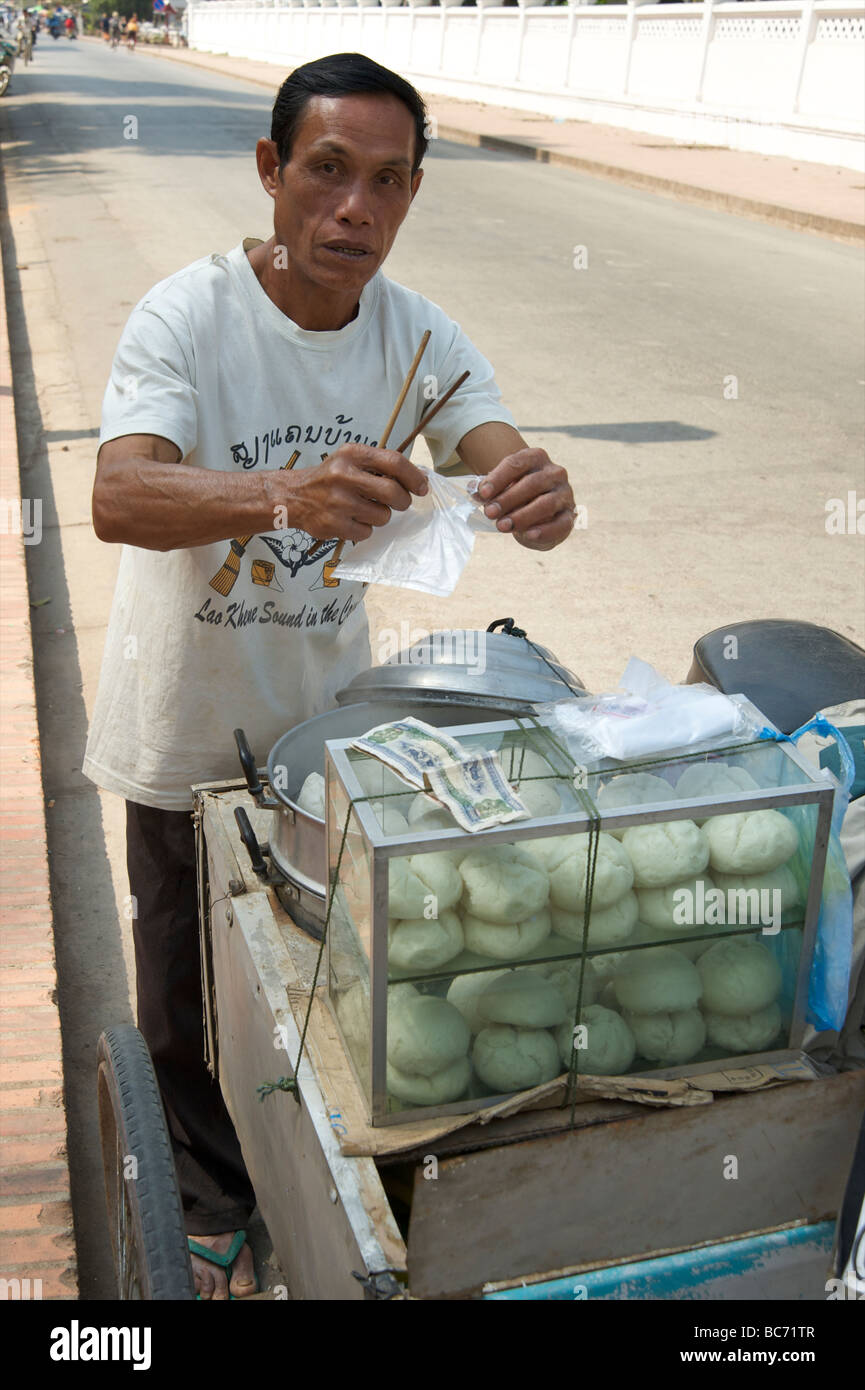 A Lao man using chopsticks to bag his Chinese dumplings from his mobile