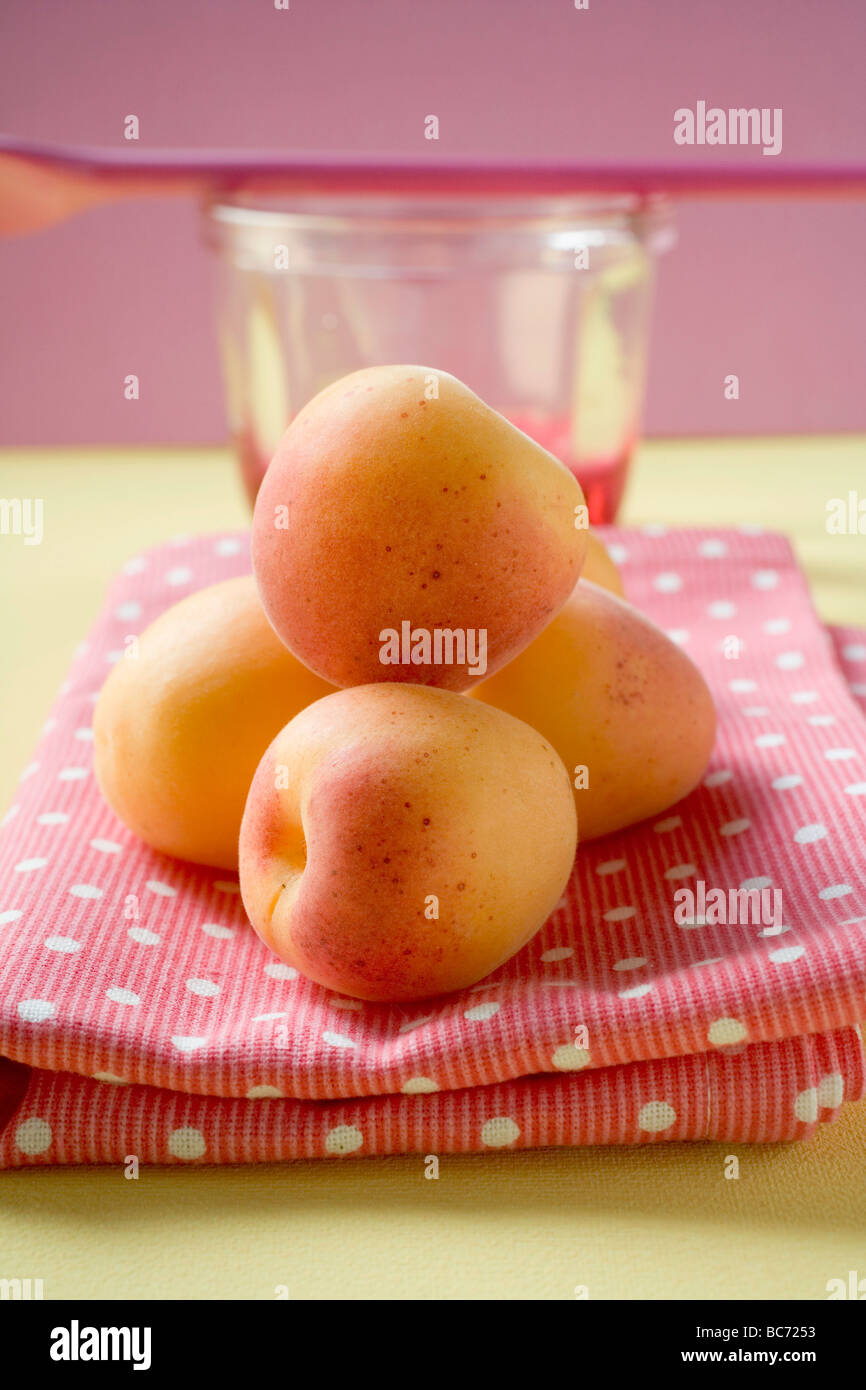 Apricots on tea towel, jam jar and cooking spoon - Stock Photo