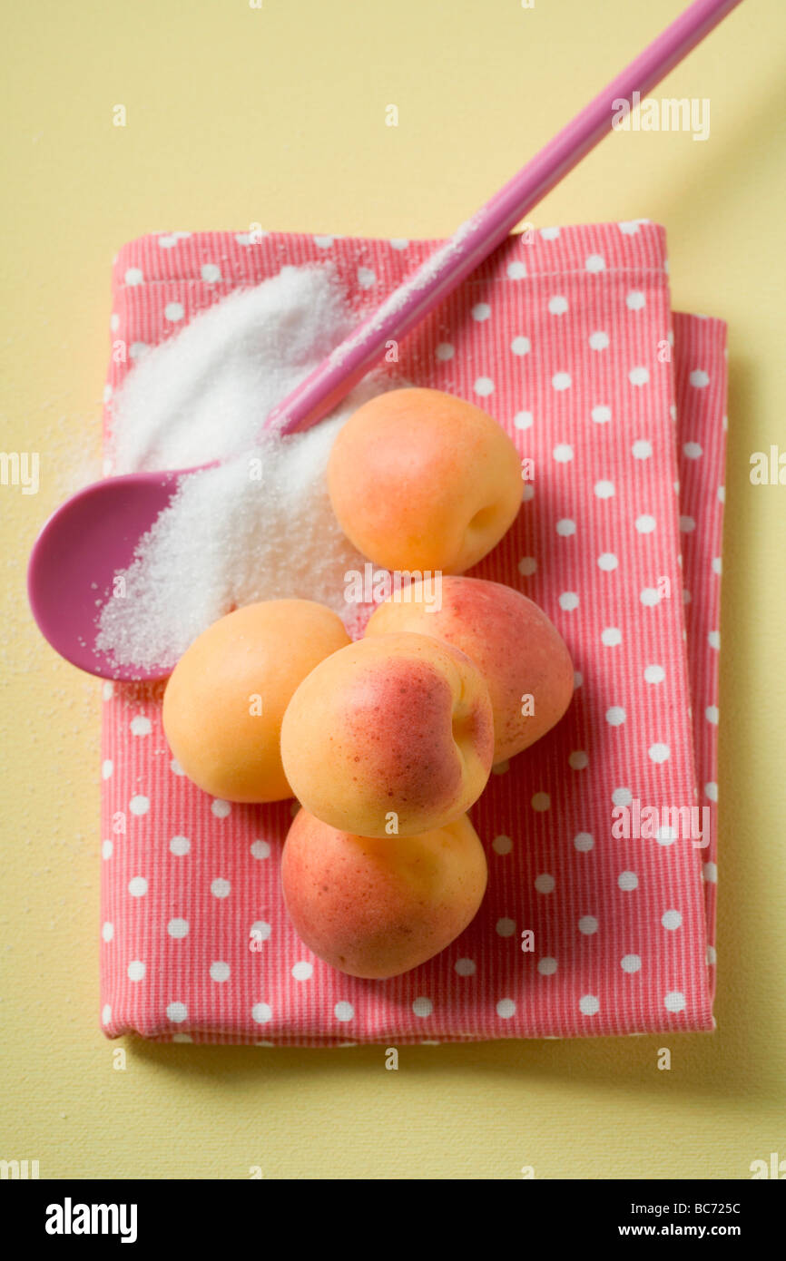 Apricots on tea towel, cooking spoon and sugar - Stock Photo