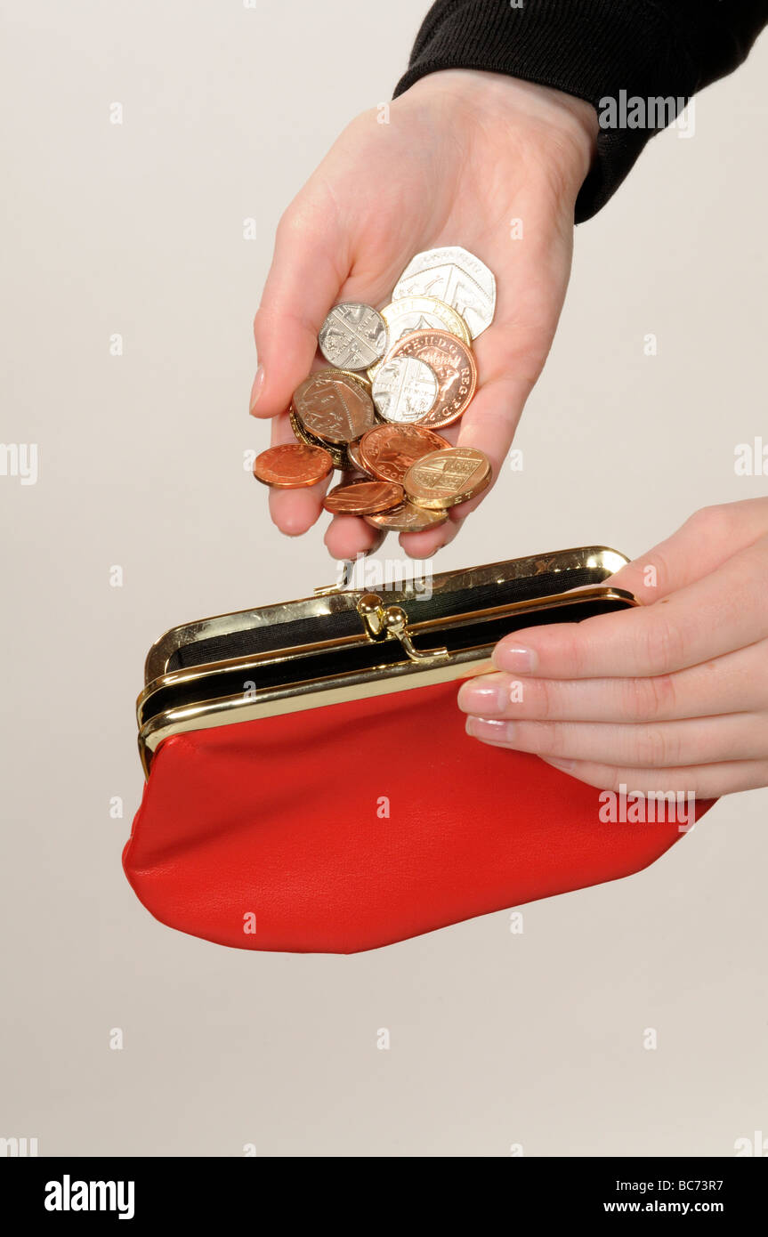 Child putting money into a red leather purse for safe keeping Stock