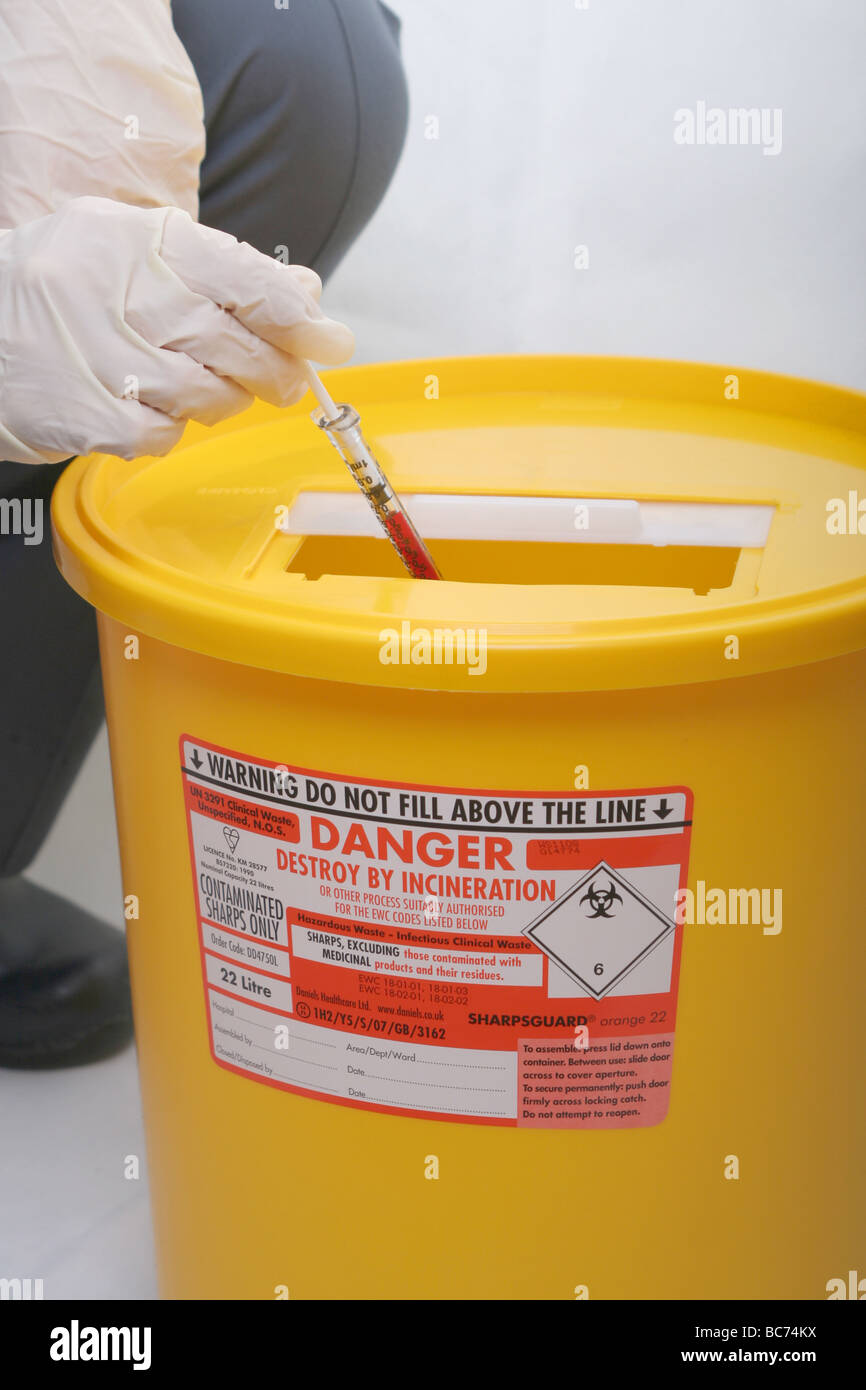 Nurse disposing of bloodfilled syringe in hospital "sharps" disposal