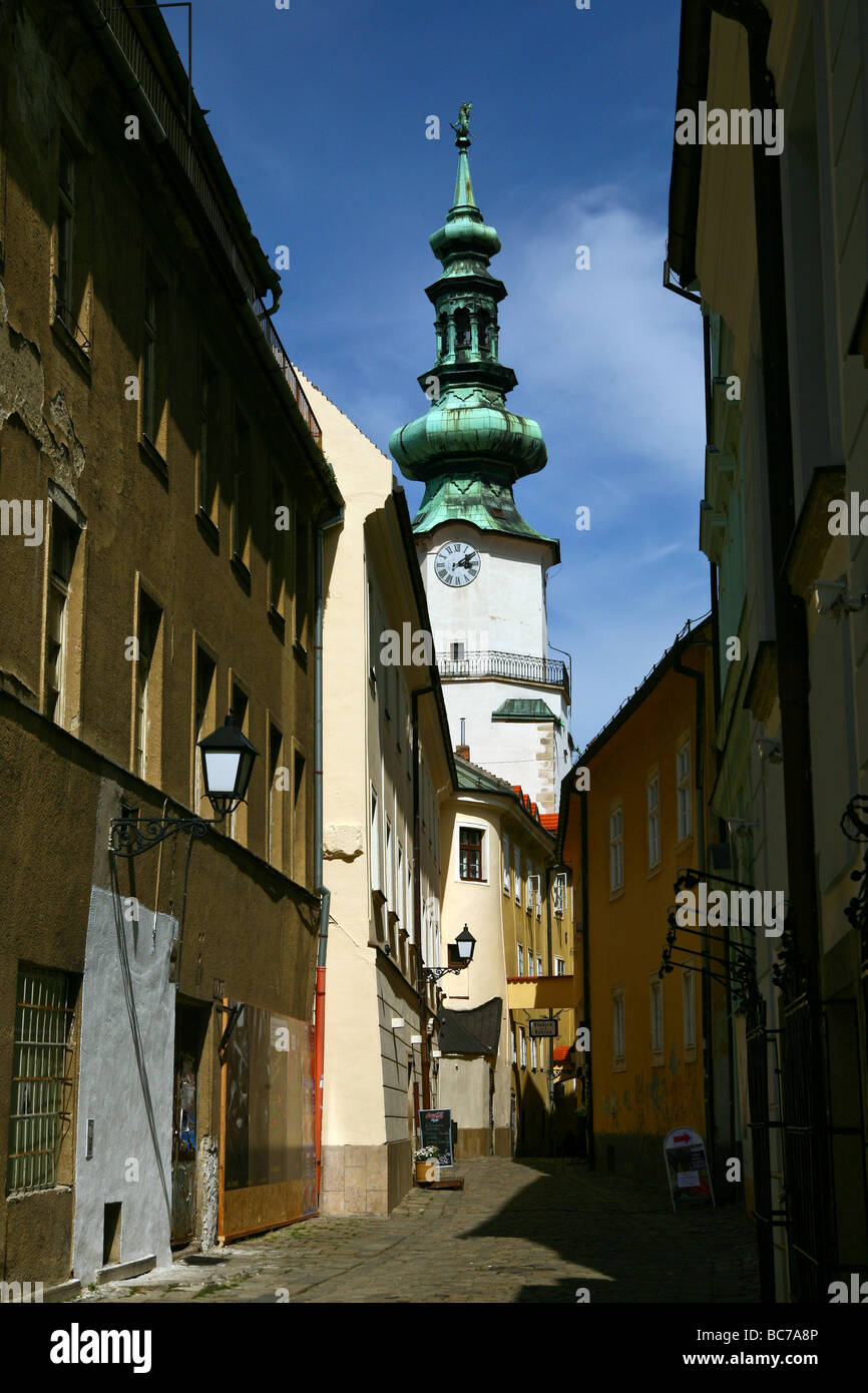 Street in old town section of Bratislava, Slovakia, with onion dome clocktower and cobblestone alley street. Stock Photo