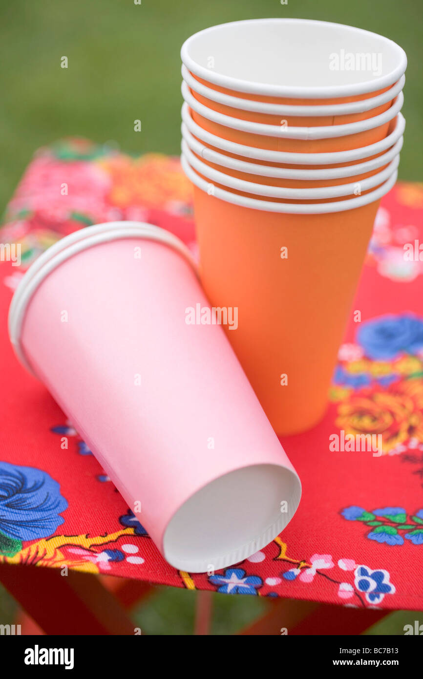Coloured paper cups on folding stool in garden Stock Photo - Alamy
