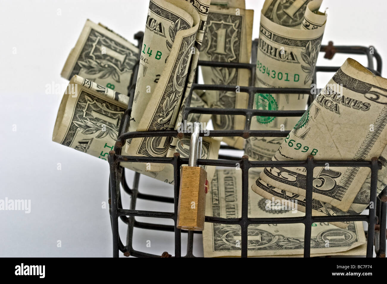Small black cage filled with American dollar bills with a small lock Stock Photo