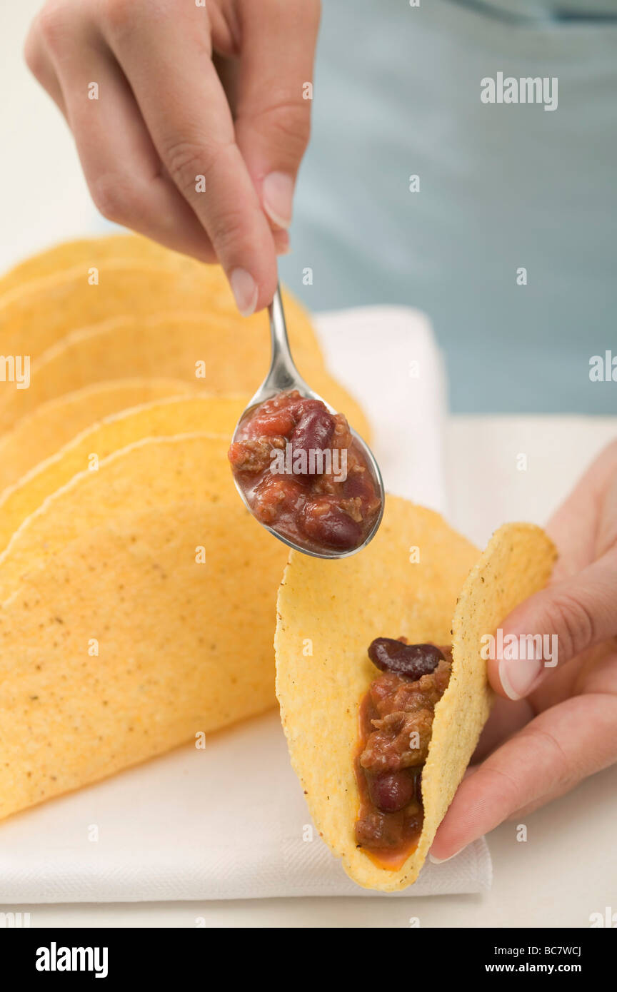 Filling tacos with chili con carne - Stock Photo