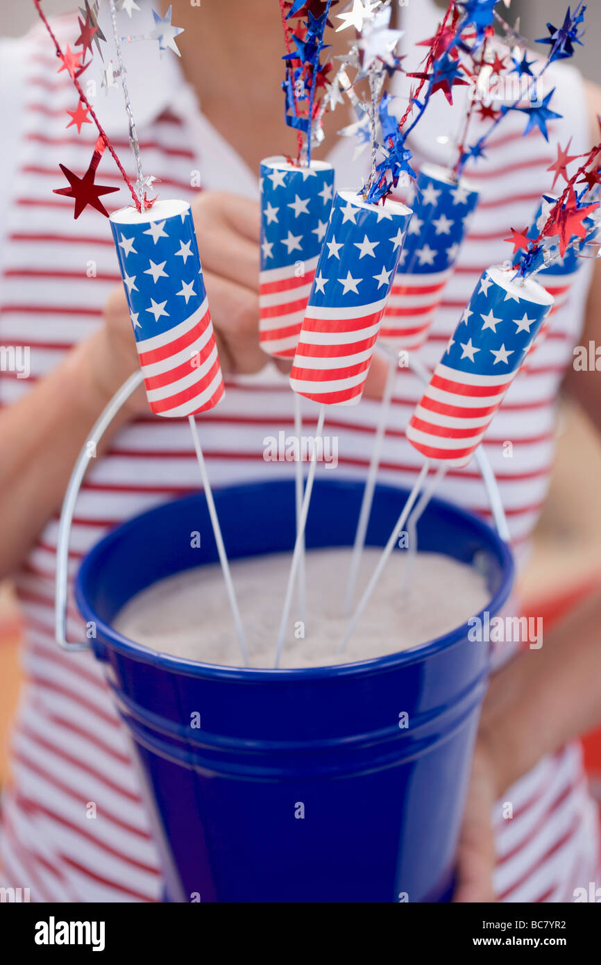 Woman holding bucket of sparklers in sand (4th of July, USA) - Stock Photo