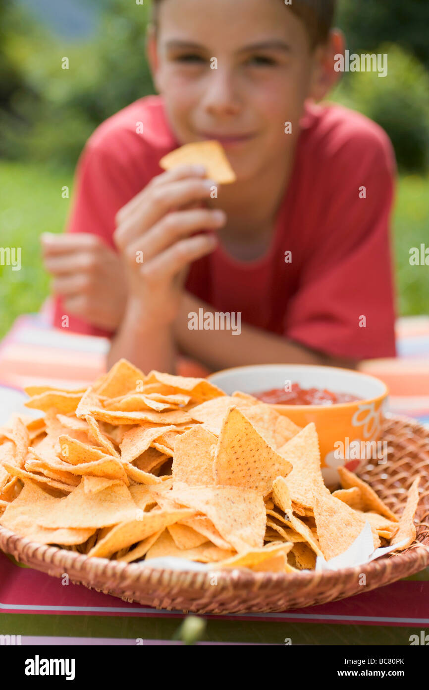 Boy eating nachos with salsa in garden Stock Photo Alamy